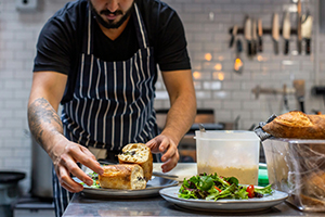 Chef plating two meals inside of a kitchen